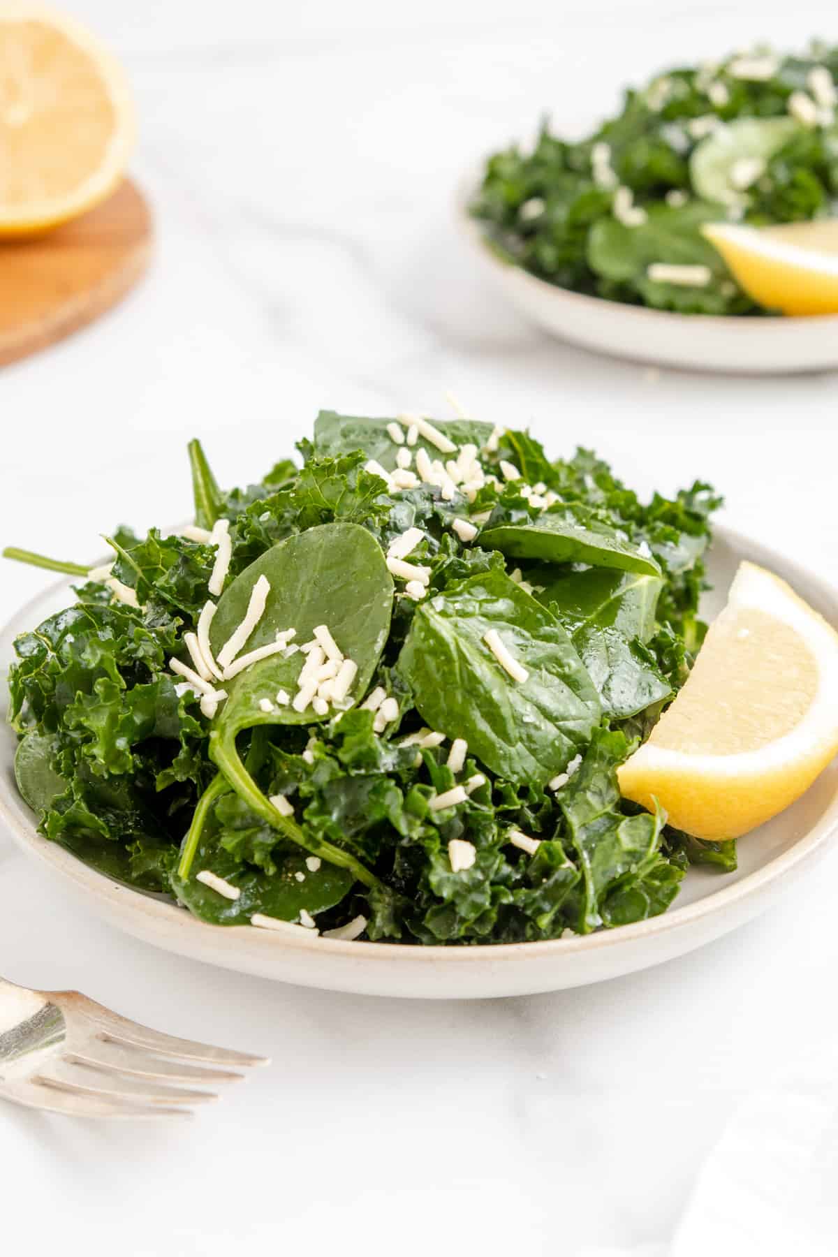 Kale and spinach salad in a bowl topped with a lemon vinaigrette and parmesan.