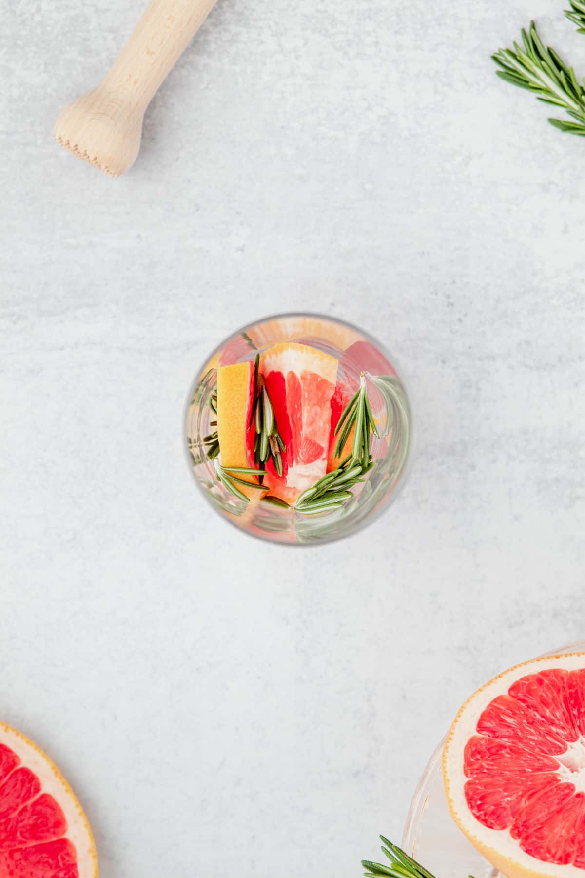Grapefruit wedges and rosemary in a glass.