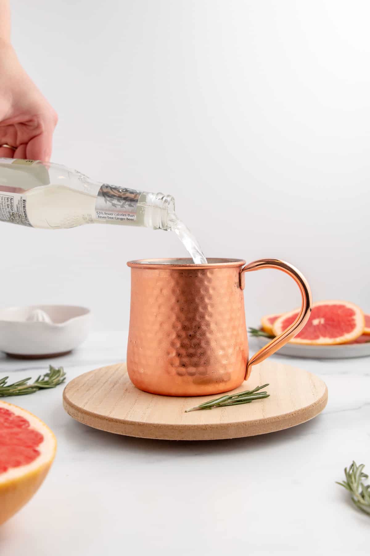 Pouring ginger beer into a copper mug to make a Moscow Mule.