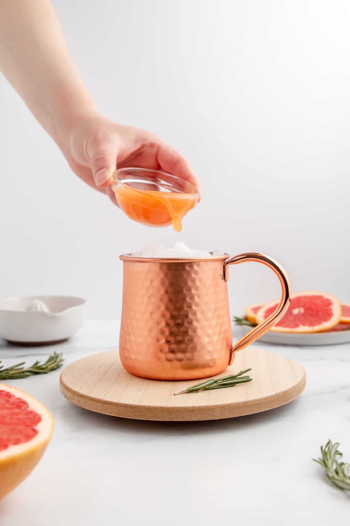 Pouring freshly squeezed grapefruit juice into a copper mug to make a grapefruit Moscow Mule.