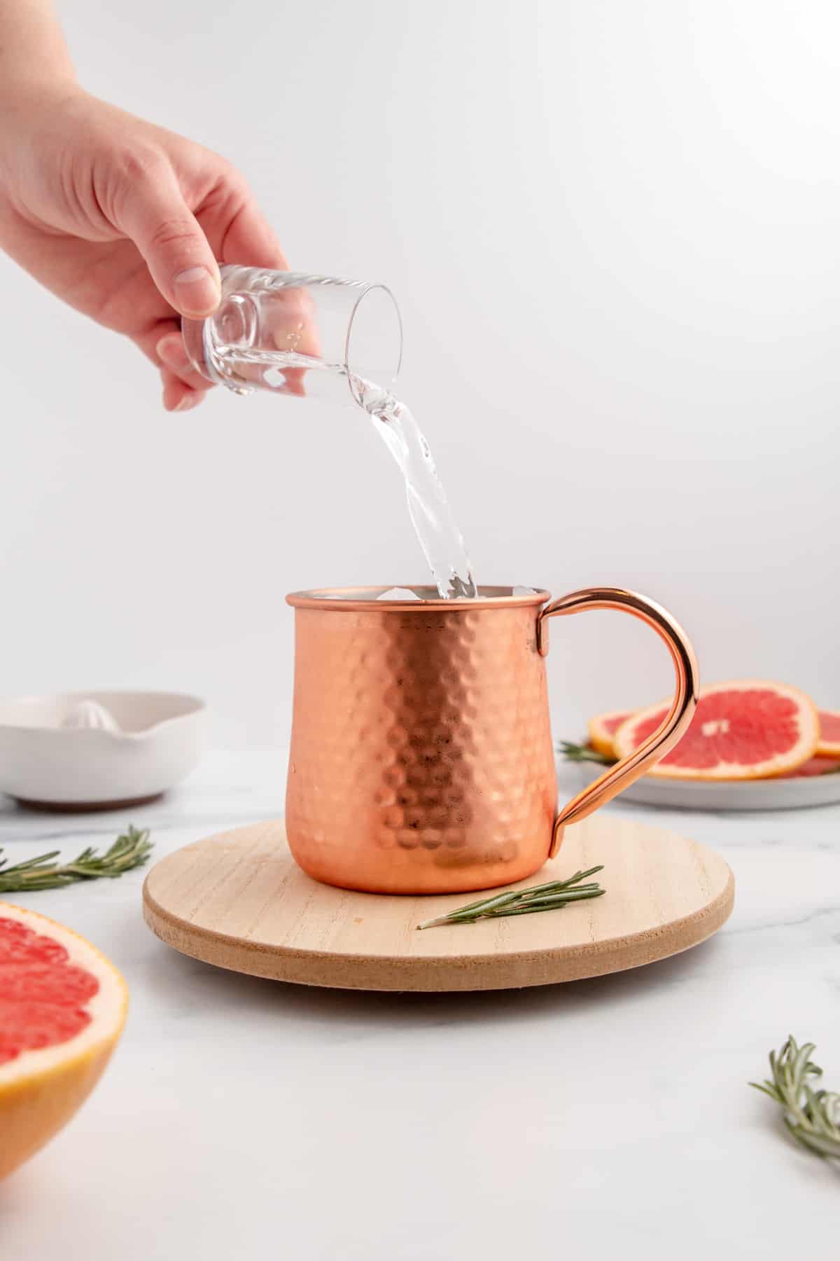 Pouring vodka into a copper mug to make a Moscow Mule.