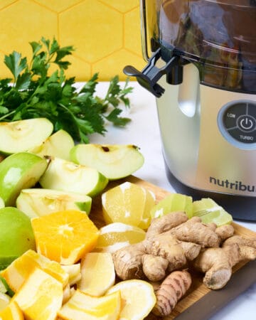 A featured image of a Nutribullet juicer with prepped ingredients on cutting board to the side.