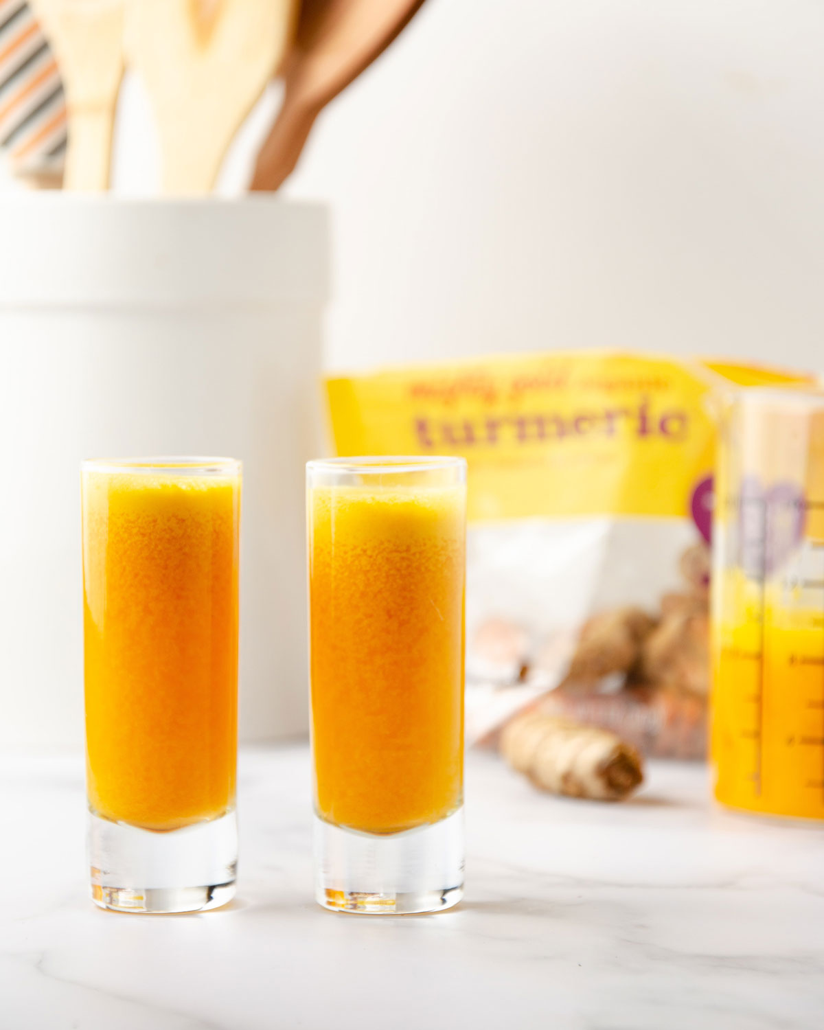 Two turmeric ginger shots on a kitchen counter.