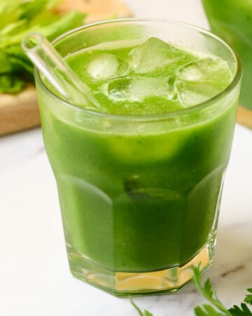A glass of green goddess juice with apple, celery, and cucumber.