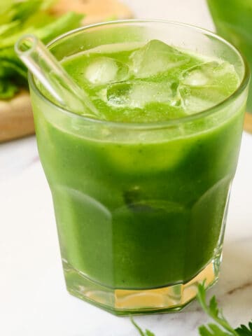 A glass of green goddess juice with apple, celery, and cucumber.