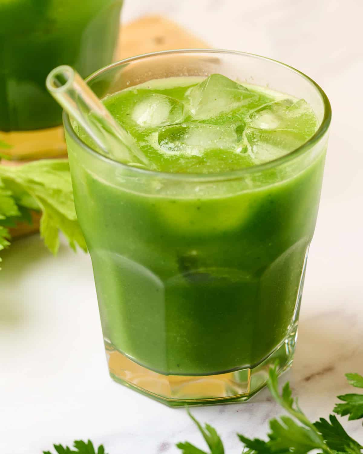 A glass of green goddess juice with apple, kale, celery, and cucumber.