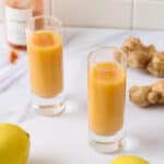 A featured image of two lemon ginger cayenne shots in two shot glasses.