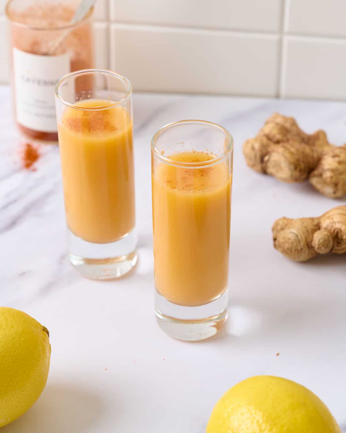Two lemon ginger cayenne shots ready to serve in two shot glasses.