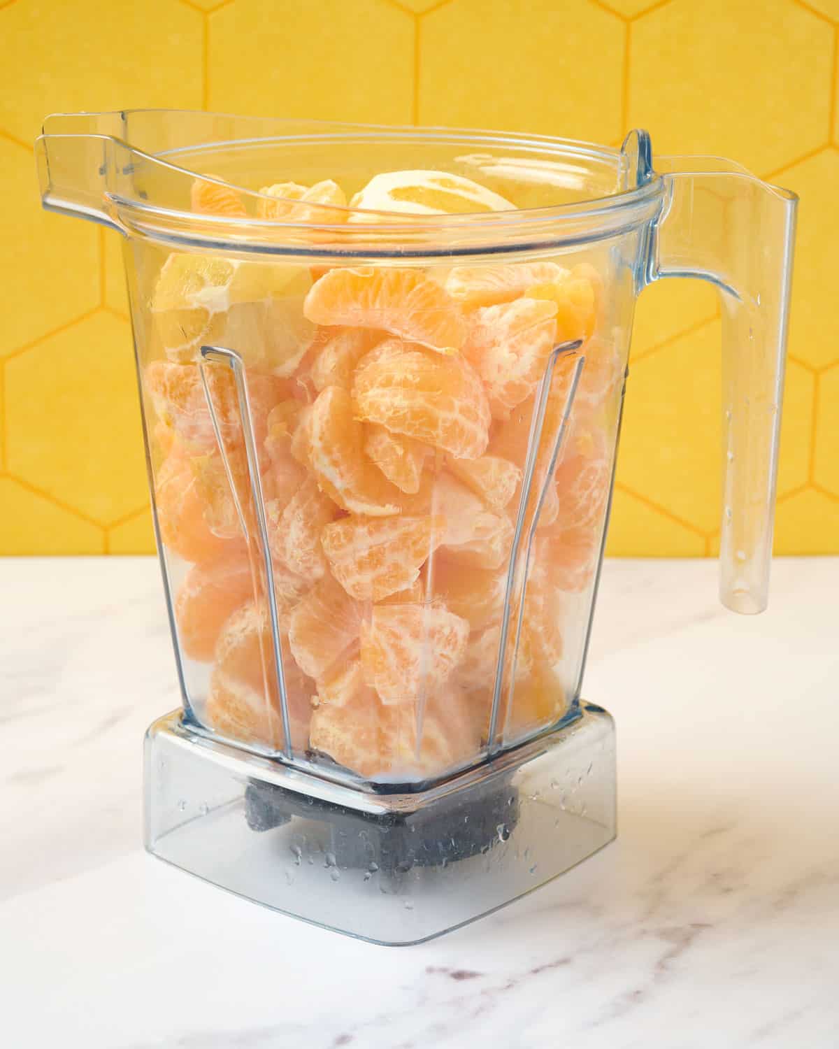 Peeled mandarins and lemons in a blender prepared to make mandarin juice.