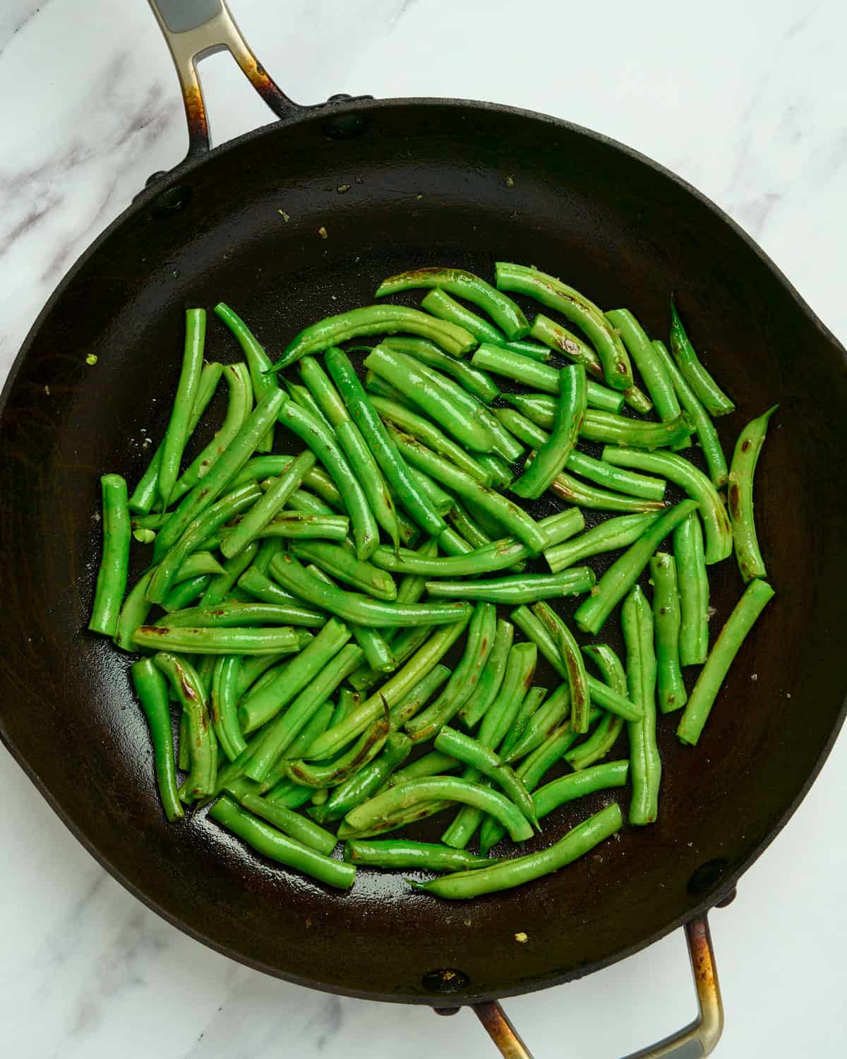 Charred green beans in a skillet.