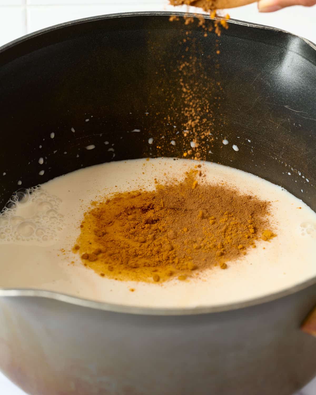 Adding turmeric and cinnamon to a oat milk turmeric latte.