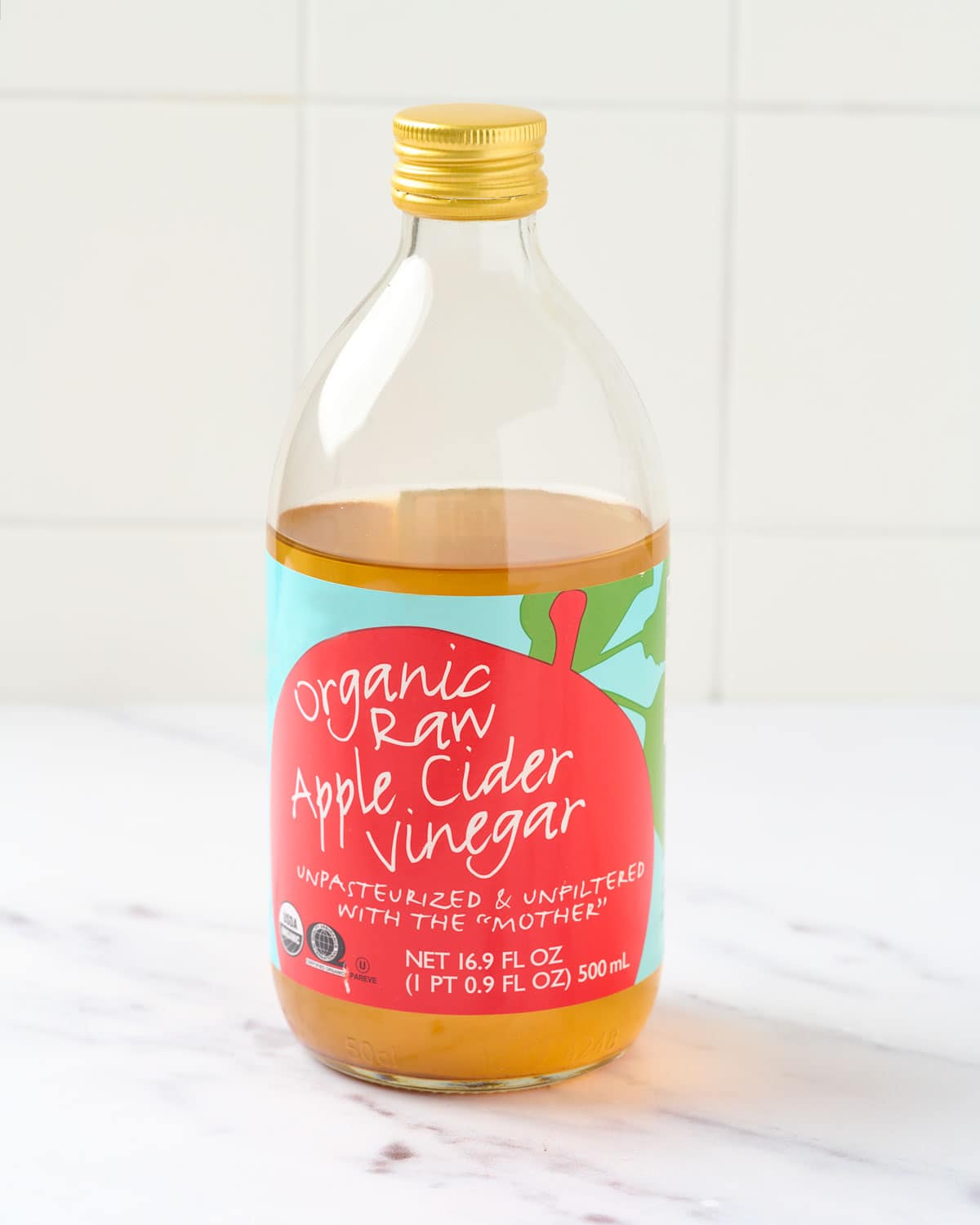 A bottle of apple cider vinegar on marble countertop.
