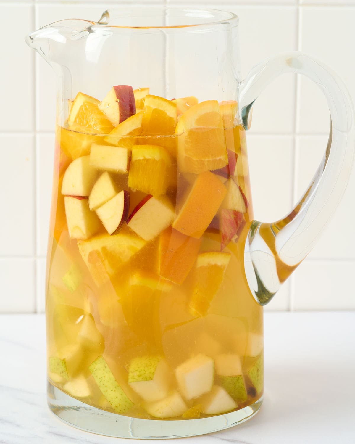 Making fall white wine sangria in pitcher.