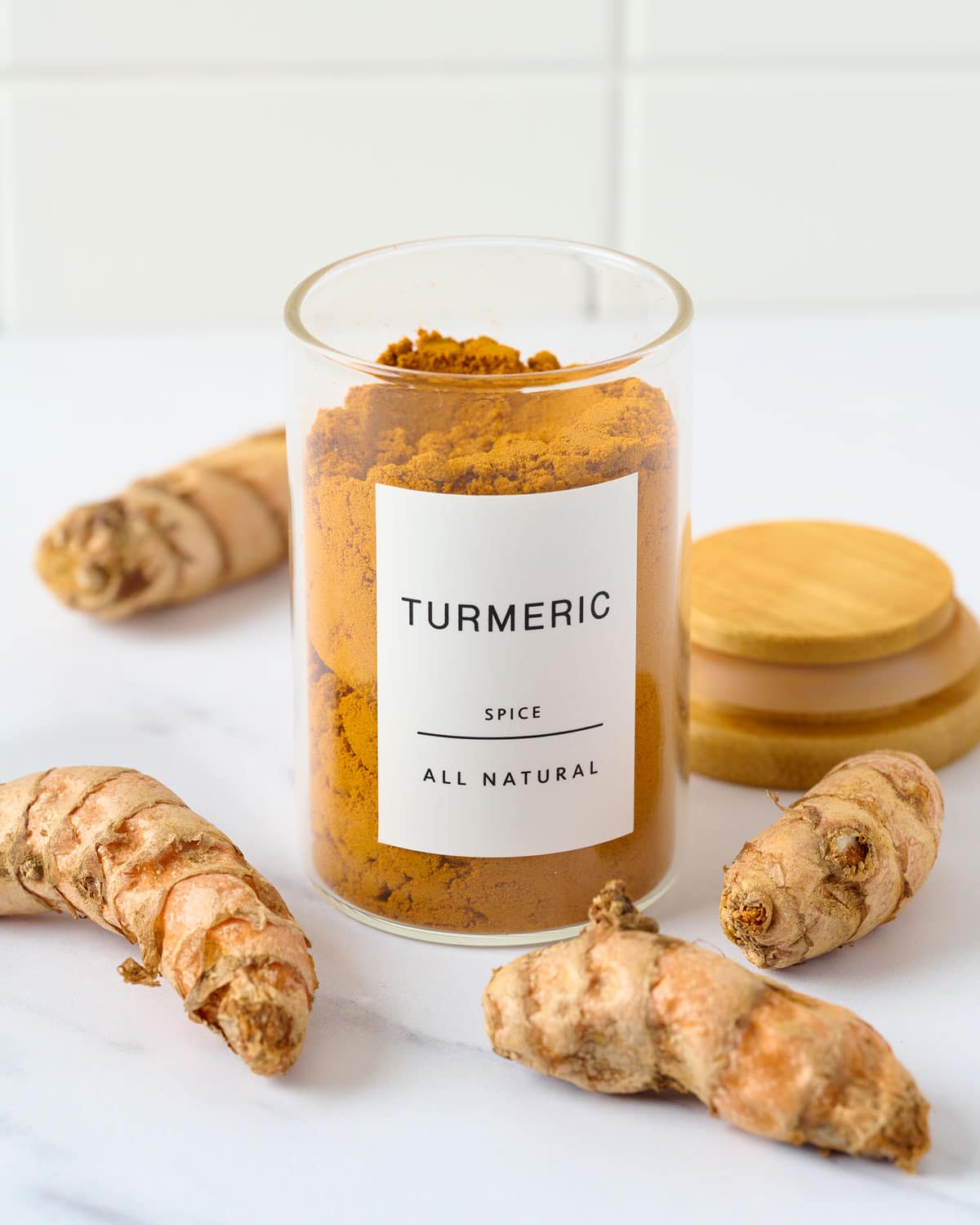 Ground turmeric and whole turmeric on marble.