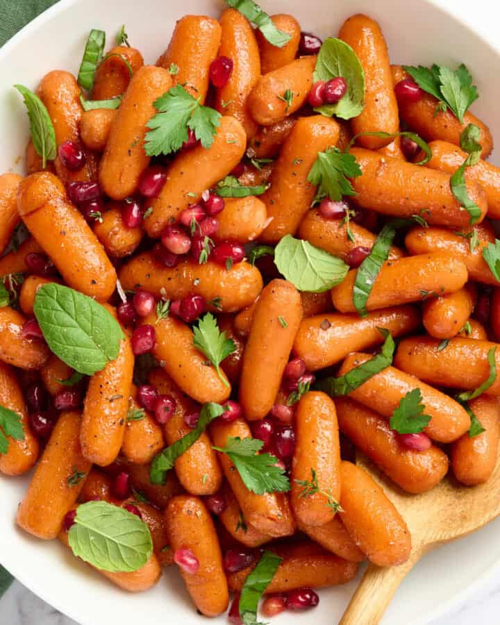 Maple balsamic glazed carrots topped with pomegranate seeds and fresh herbs.