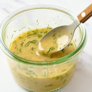 Creamy dill mustard dressing in a small bowl with a spoon.