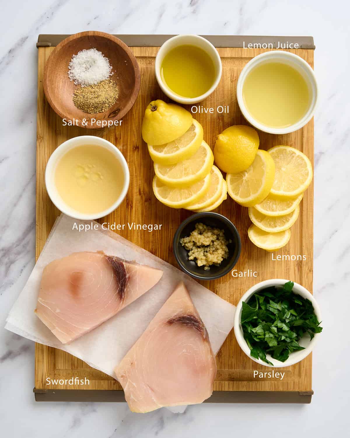 Ingredients needed to make lemon pepper swordfish on a cutting board.