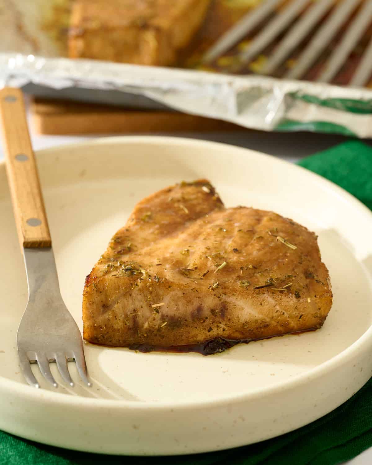 Baked balsamic swordfish with Italian seasoning on a plate.