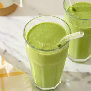 Kale and spinach smoothie in a glass with a straw.