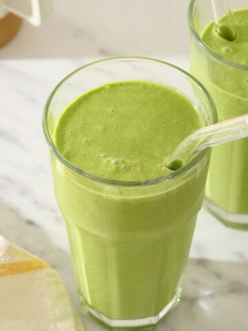 Kale and spinach smoothie in a glass with a straw.